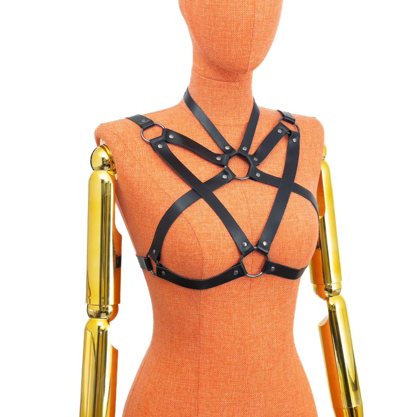 Black leather harness on an orange mannequin with gold arm pieces against a white background