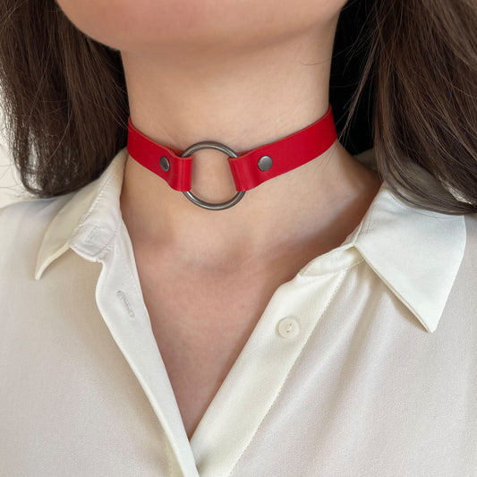 Red leather choker with black ring – angled front view on model with ivory shirt.