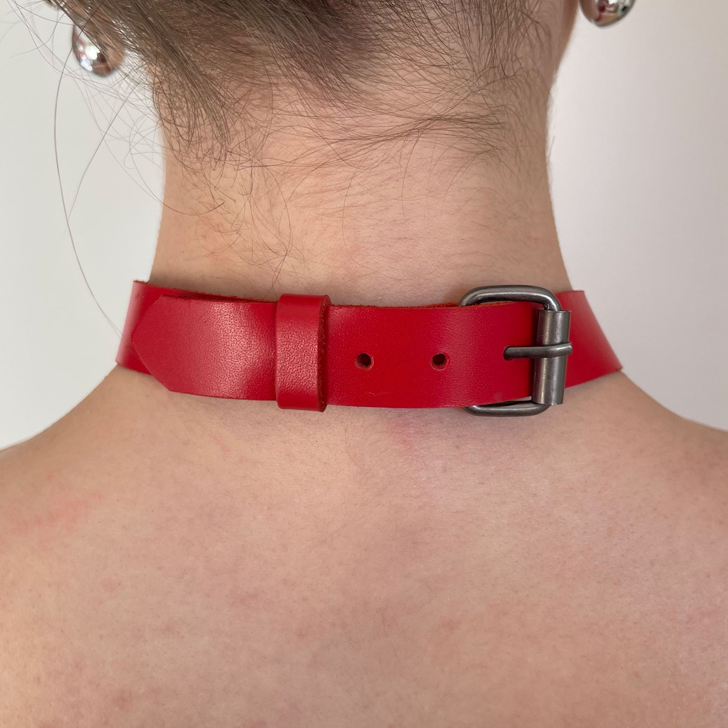 Back view of red leather choker with adjustable dark nickel buckle and smooth leather strap.