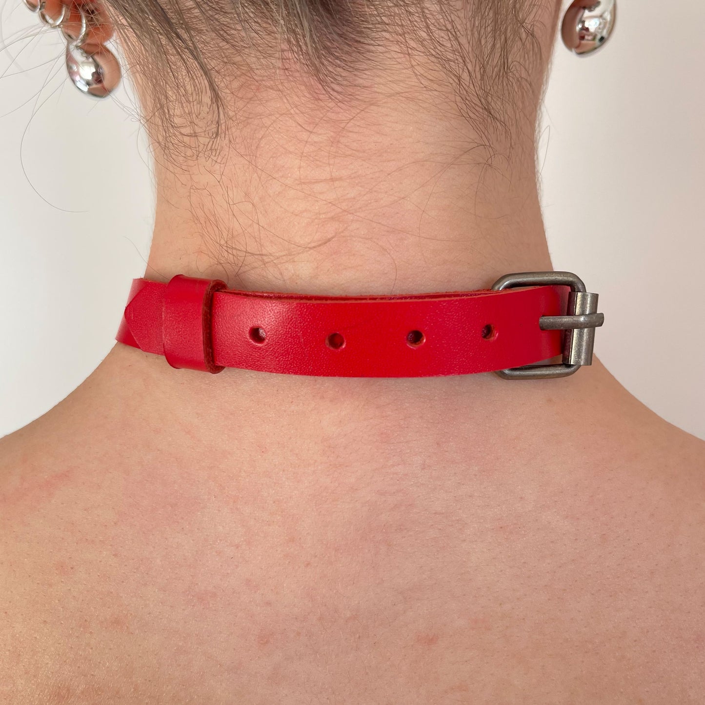 Back view of red leather choker with black buckle and smooth finish.