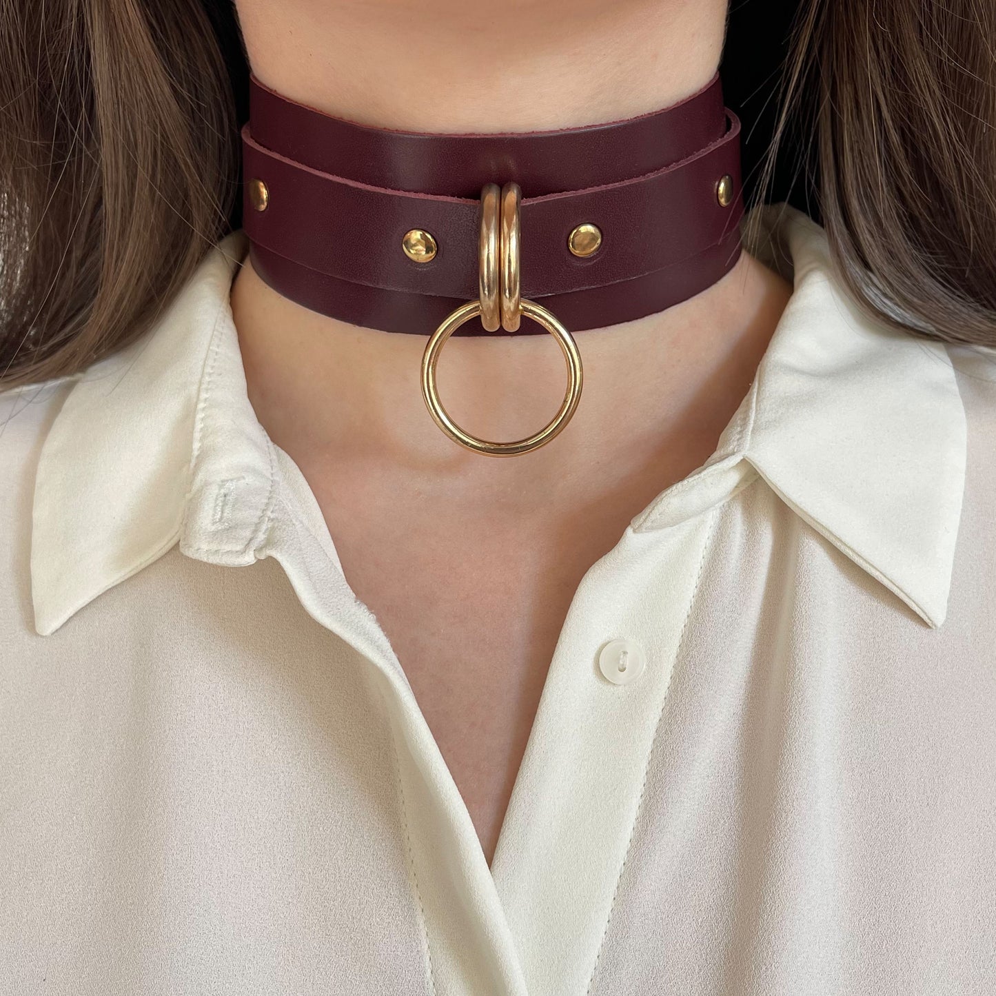 Wide marsala leather choker with double gold rings and hardware – front view on model.