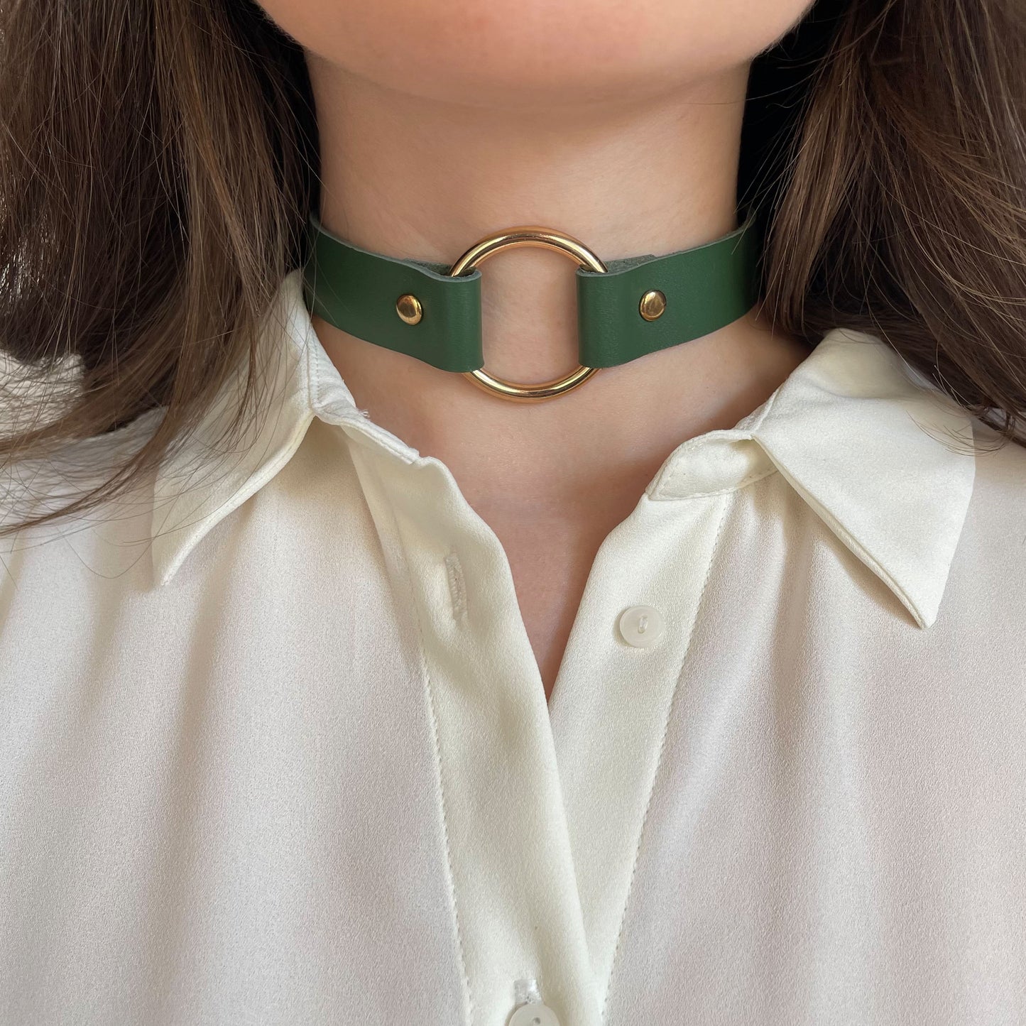 Front view of green leather choker with shiny gold O-ring, styled on neck with white shirt