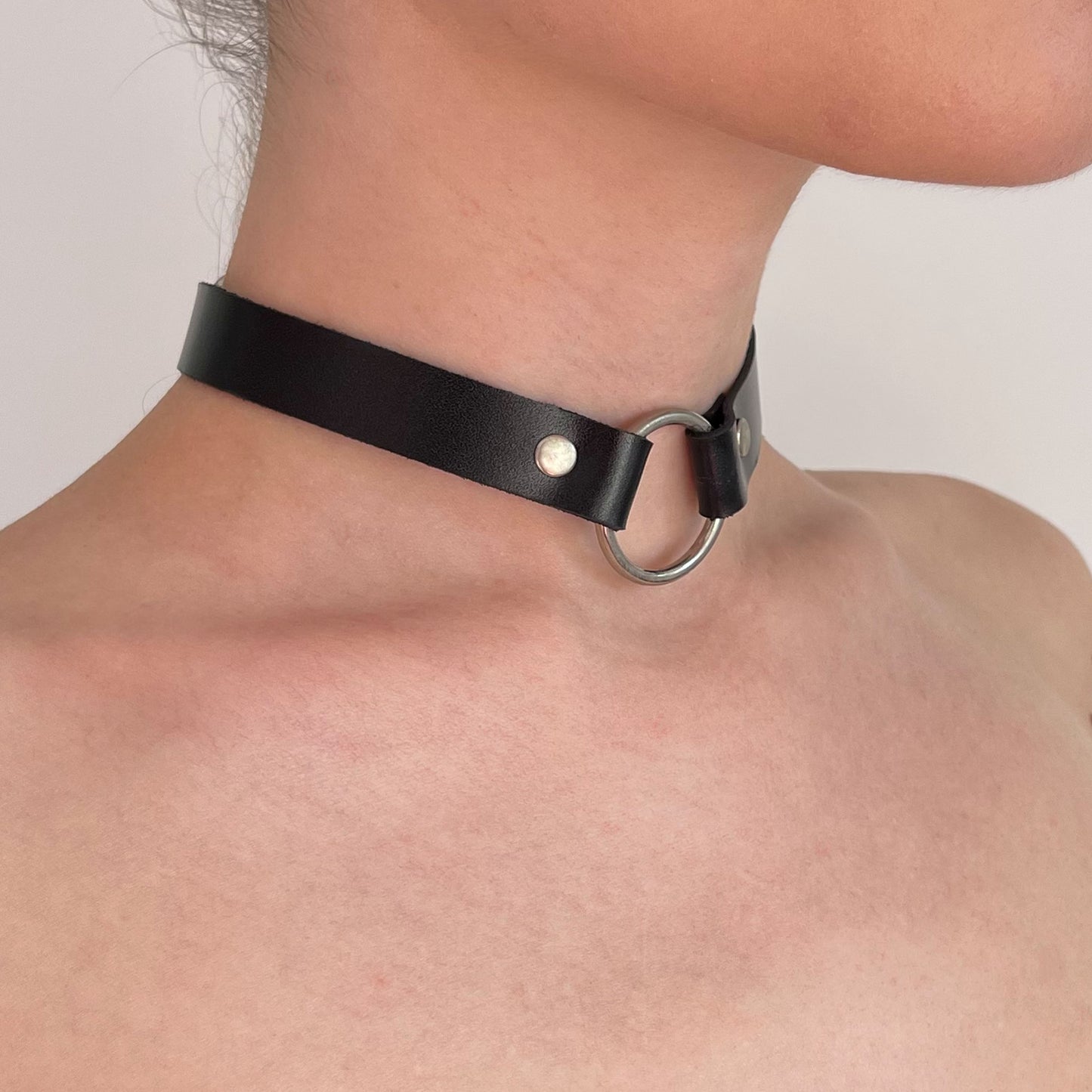 Black leather choker with silver O-ring – angled side view on bare neck