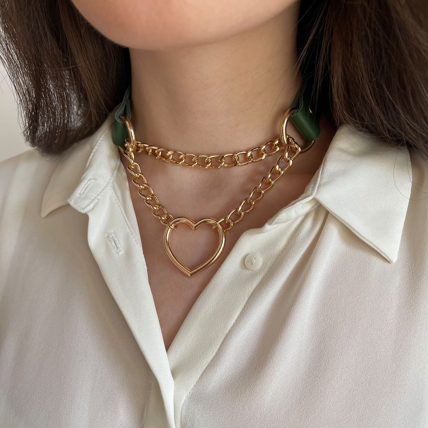 Green leather choker with gold heart-shaped hardware on neck, side angle