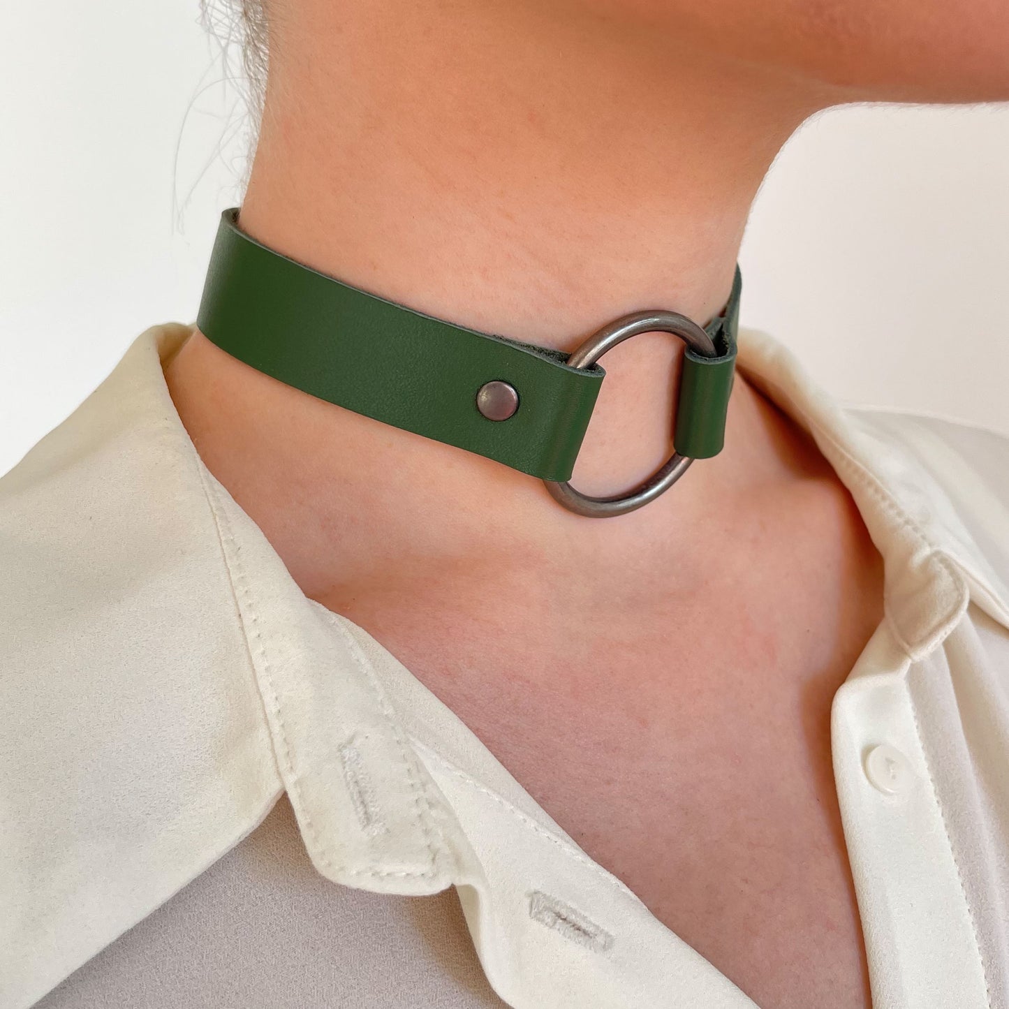 Side close-up of green leather choker with matte gunmetal O-ring and rivets, styled with blouse