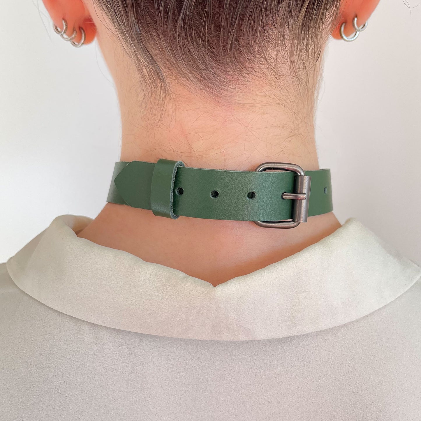 Back view of green choker with gunmetal buckle and adjustment holes, worn over blouse collar