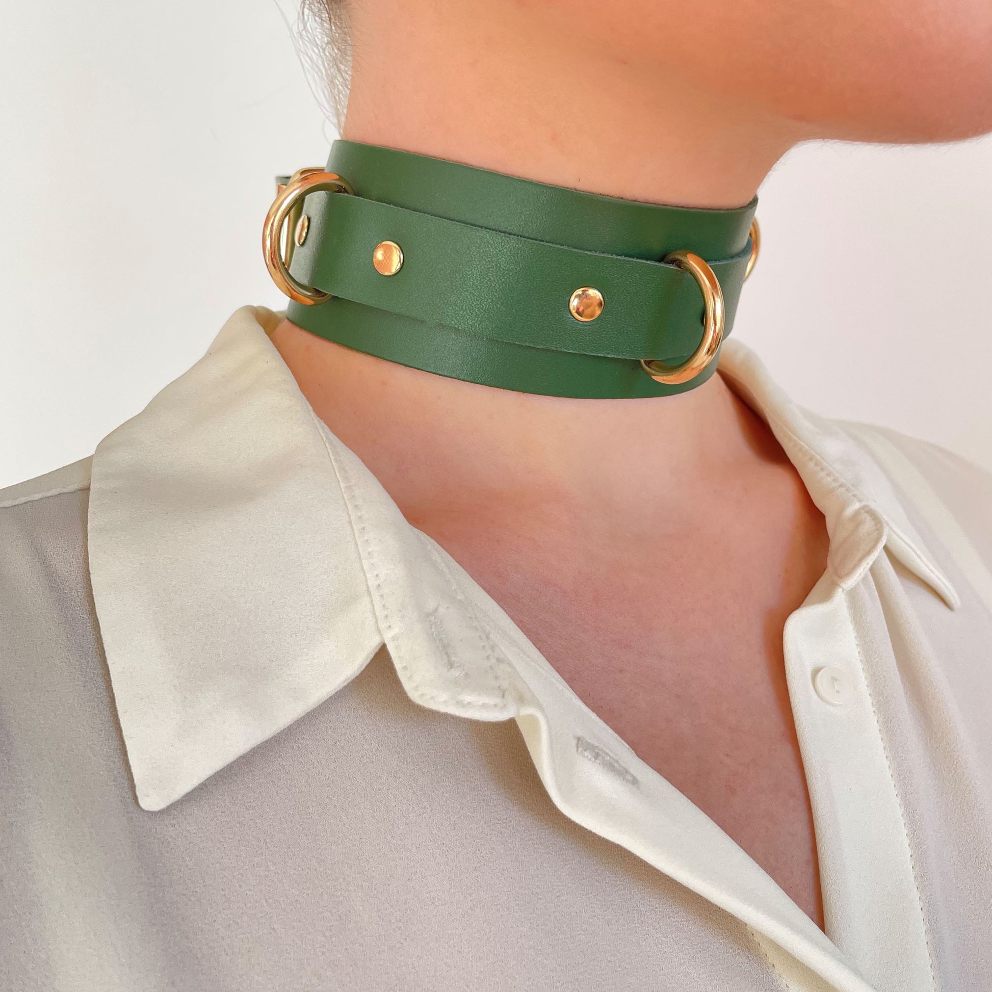 Green leather choker with gold hardware – side view on neck over white shirt.