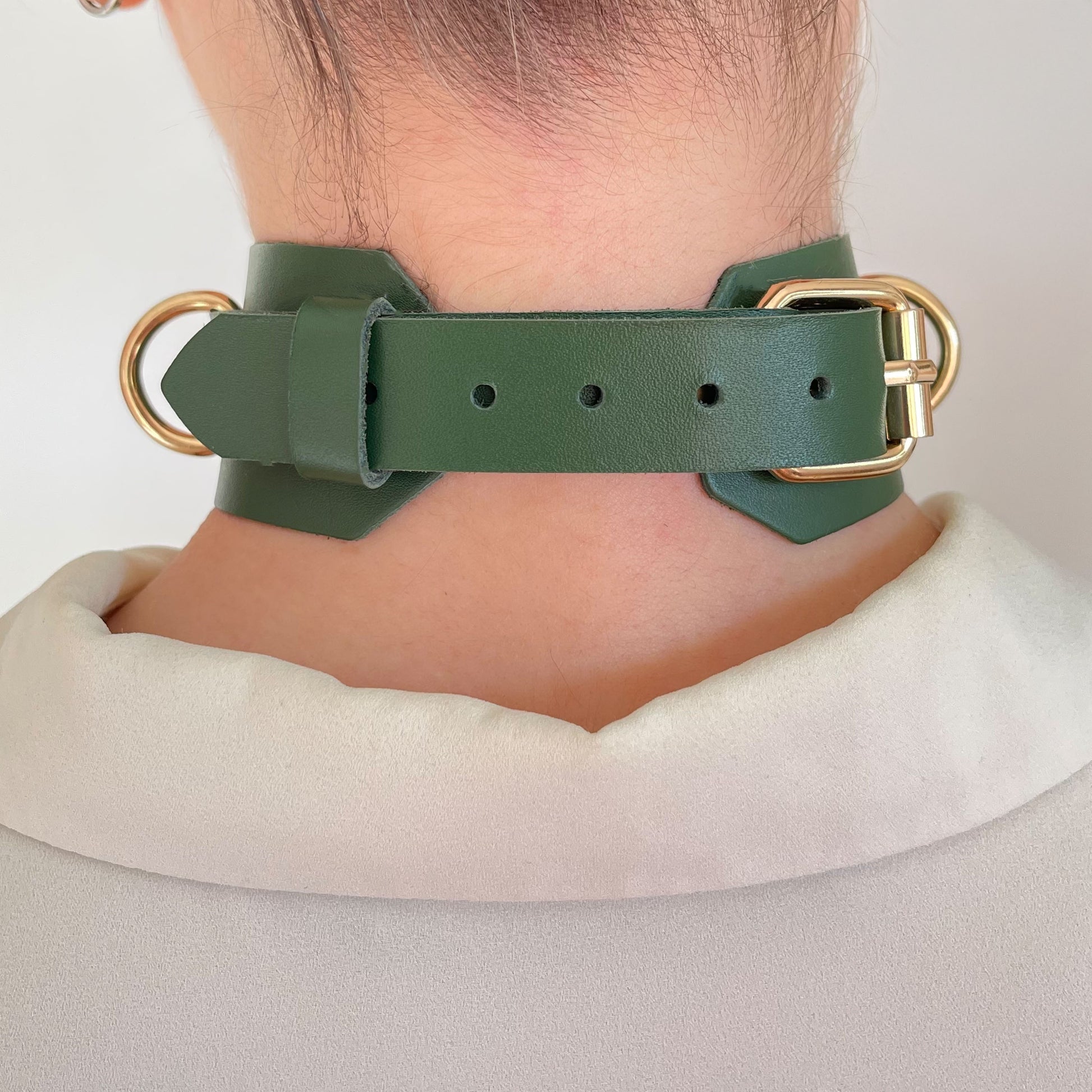 Back view of green leather choker with gold buckle and adjustment holes.