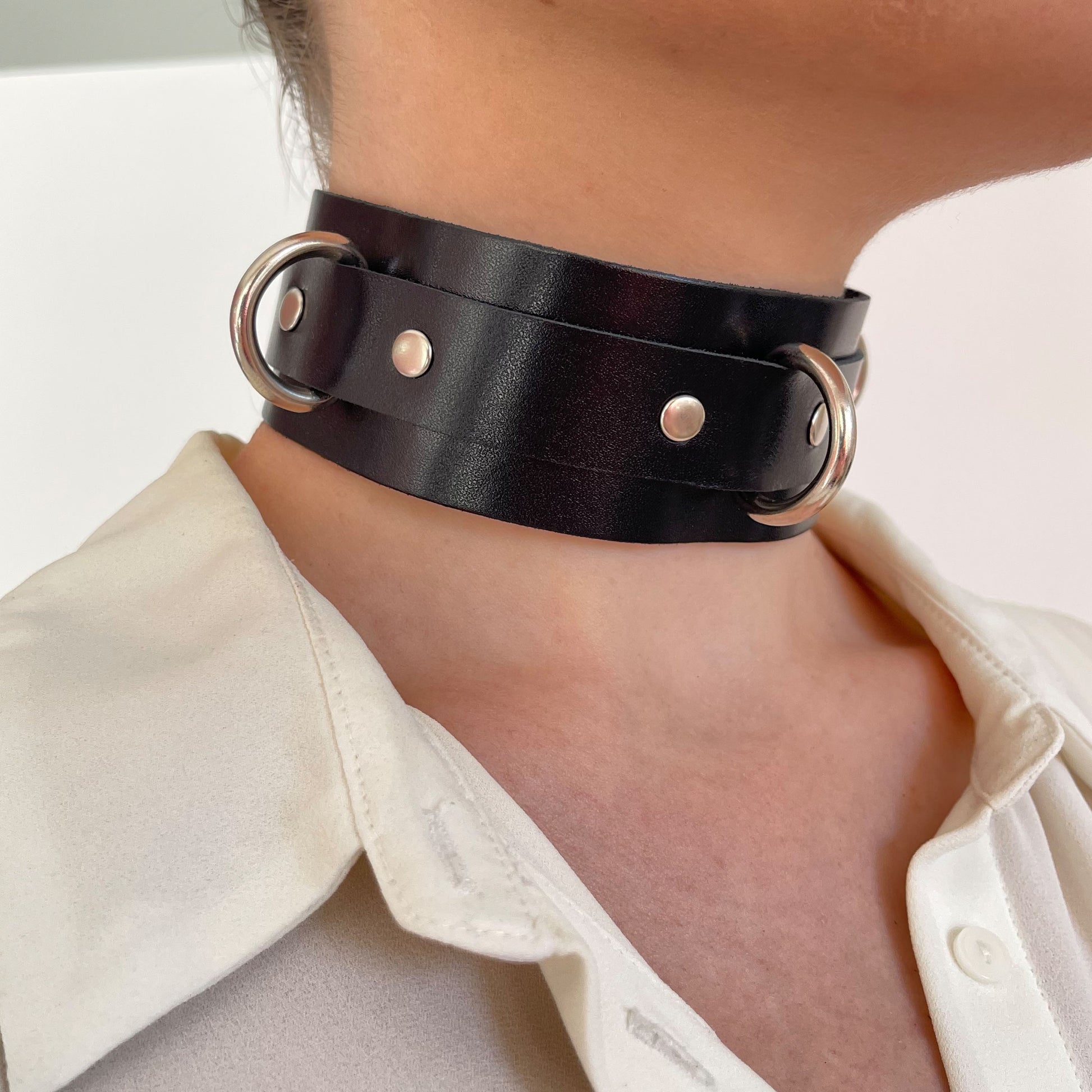 Black leather choker with silver hardware – side view on model with cream shirt.