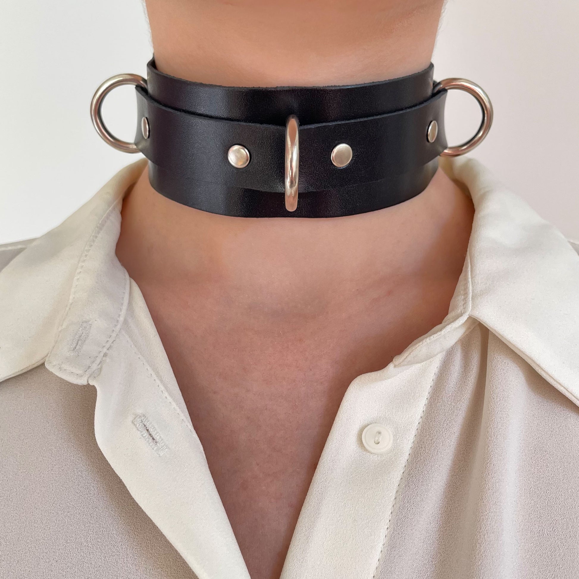 Black leather choker with silver D-rings – front view centered on neck.