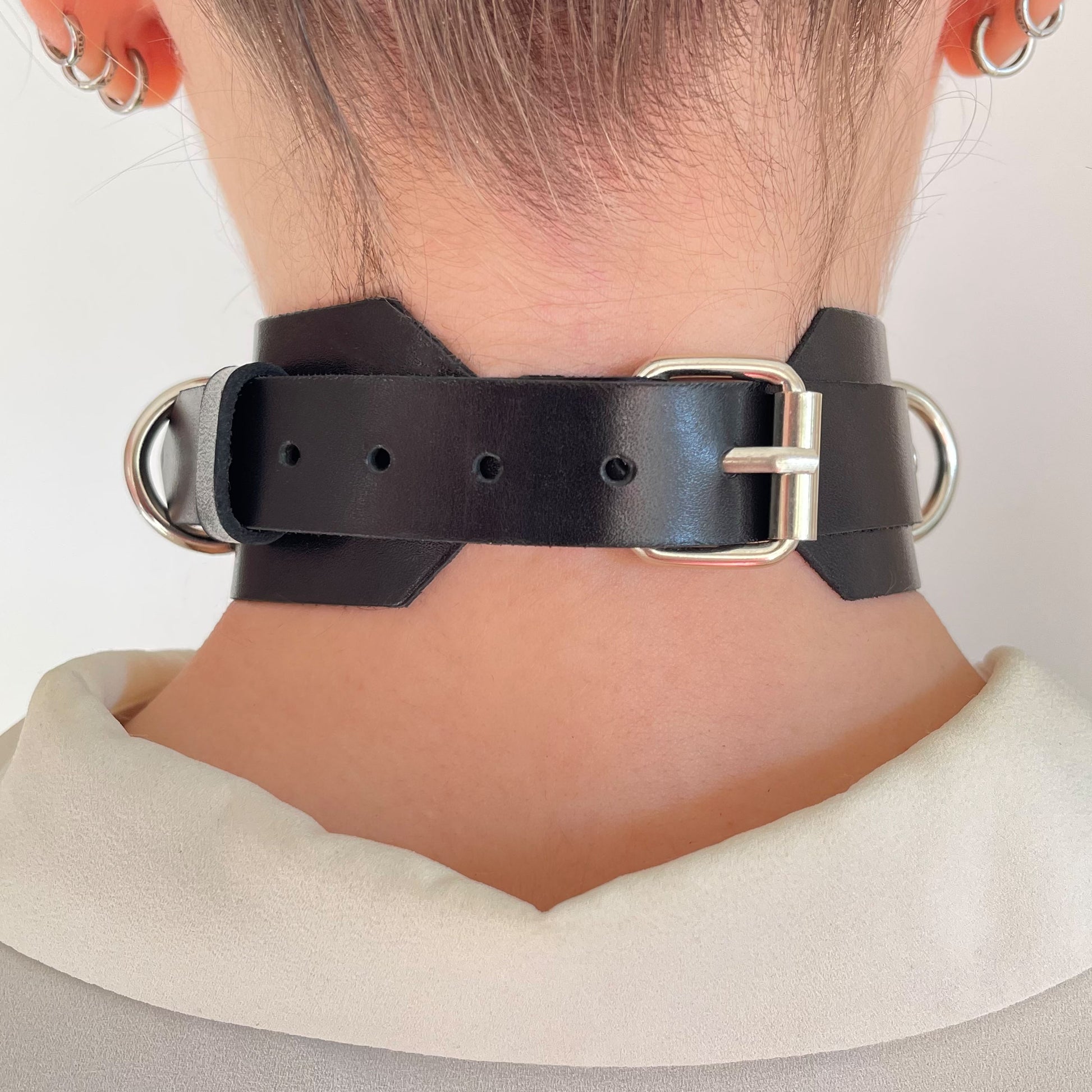 Back view of black leather choker with silver buckle and rounded strap ends.