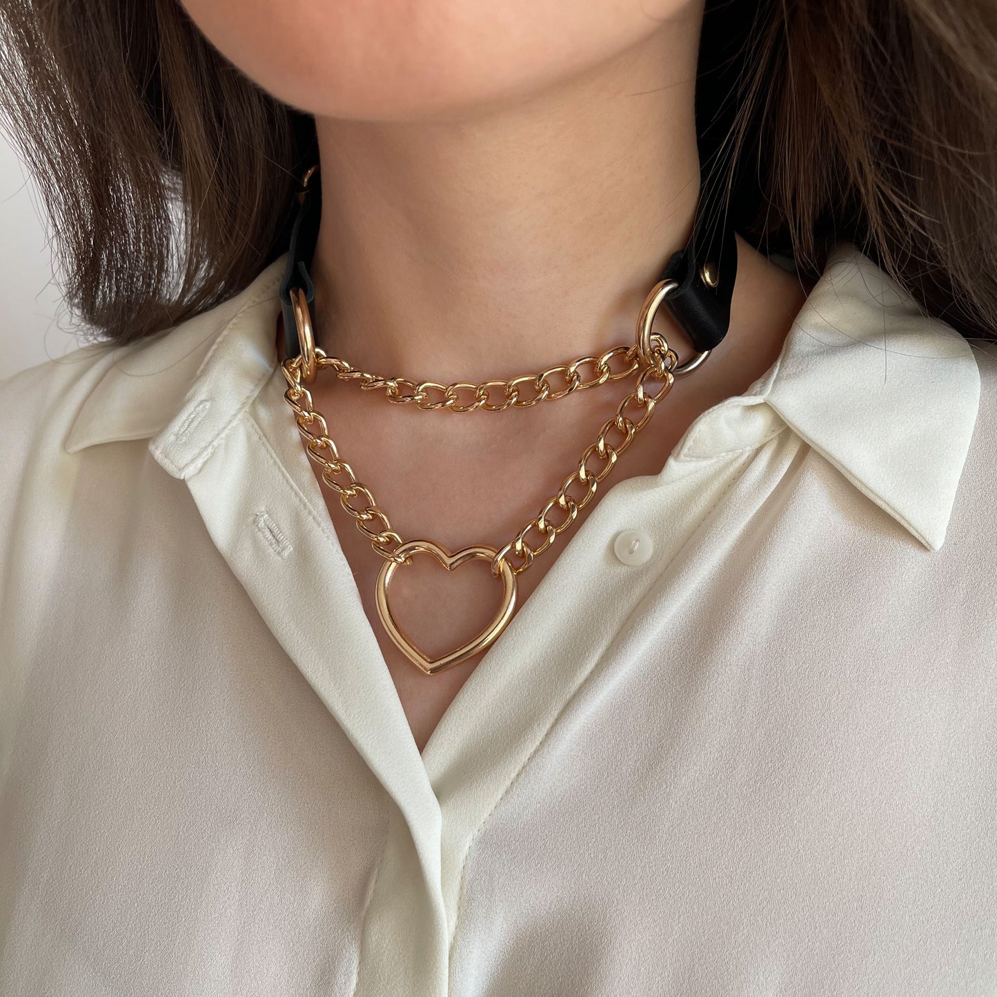 Black leather choker with gold chain and heart ring, side close-up