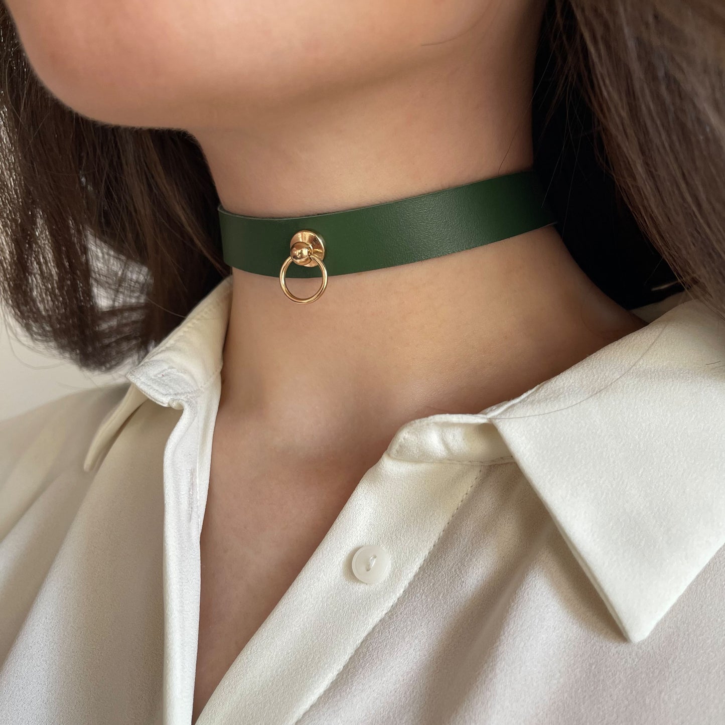 Minimalist green leather choker with a central gold ring. Width: 1.5 cm (0.59 in). Made from semi-matte genuine leather (1.4–1.8 mm thick). Pictured on a woman's neck in a white shirt from the side, showing the clean shape and refined style.