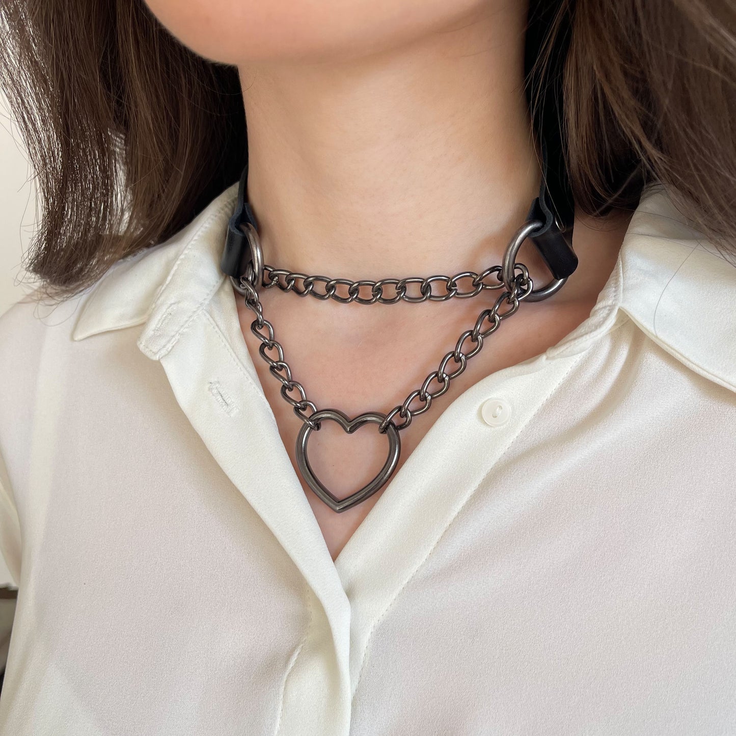 Black leather choker with dark nickel hardware and heart pendant, side angle