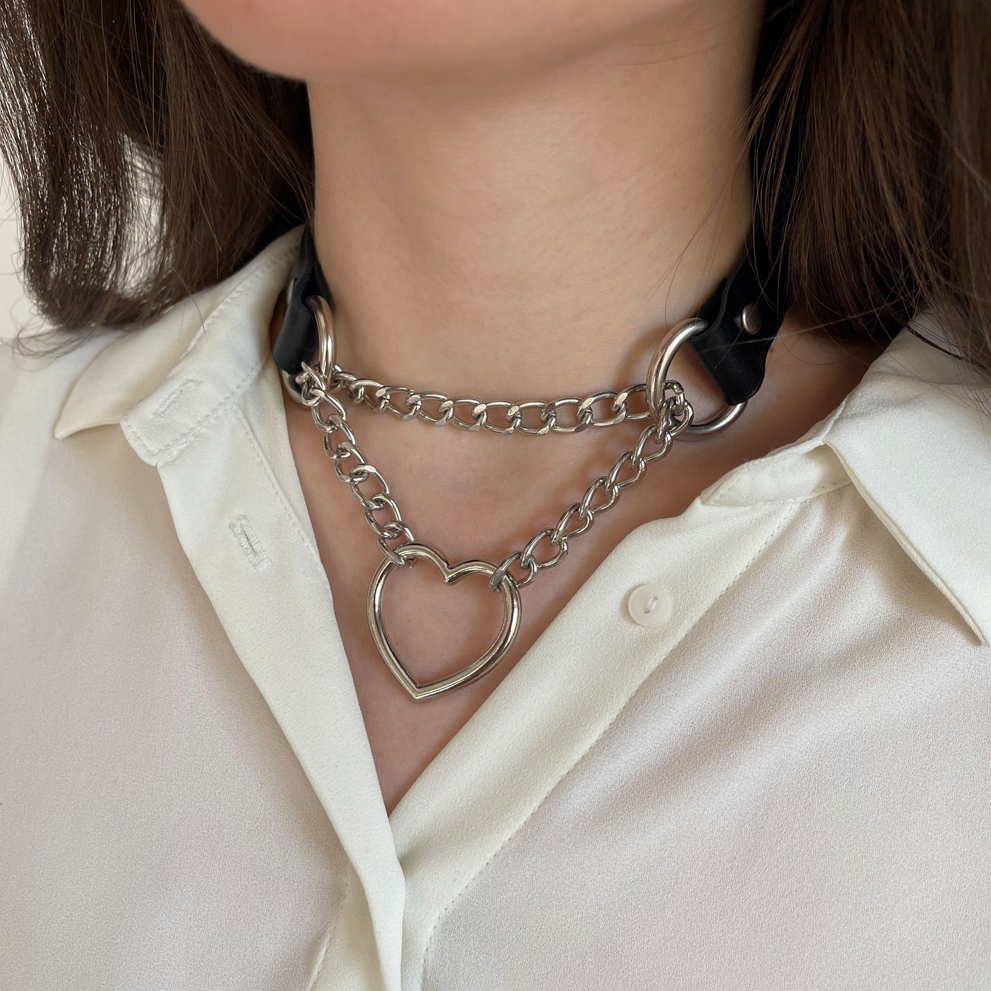 Black leather choker with silver chain and heart ring, side close-up on neck