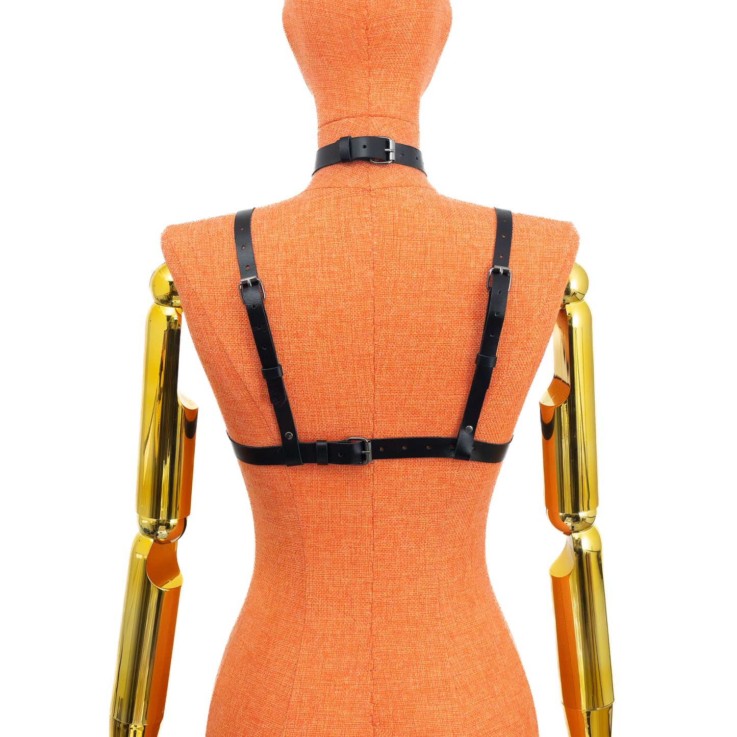 Black genuine leather gothic cross open bust chest harness bra on mannequin, dark nickel hardware, back view showing one horizontal strap with buckle closure and two vertical shoulder straps with adjustment holes and strap ends visible.