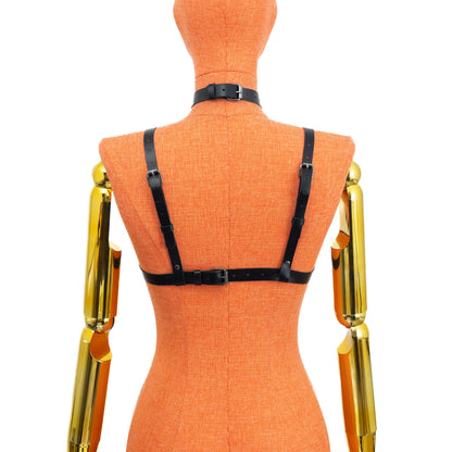 Black genuine leather gothic cross open bust chest harness bra on mannequin, dark nickel hardware, back view showing one horizontal strap with buckle closure and two vertical shoulder straps with adjustment holes and strap ends visible.
