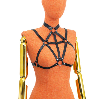 Black genuine leather gothic cross open bust chest harness bra on mannequin, dark nickel hardware, front three-quarter view showing choker connection, cross straps with spikes, lower ring between breasts and horizontal underbust strap shaping bra outline without cups.