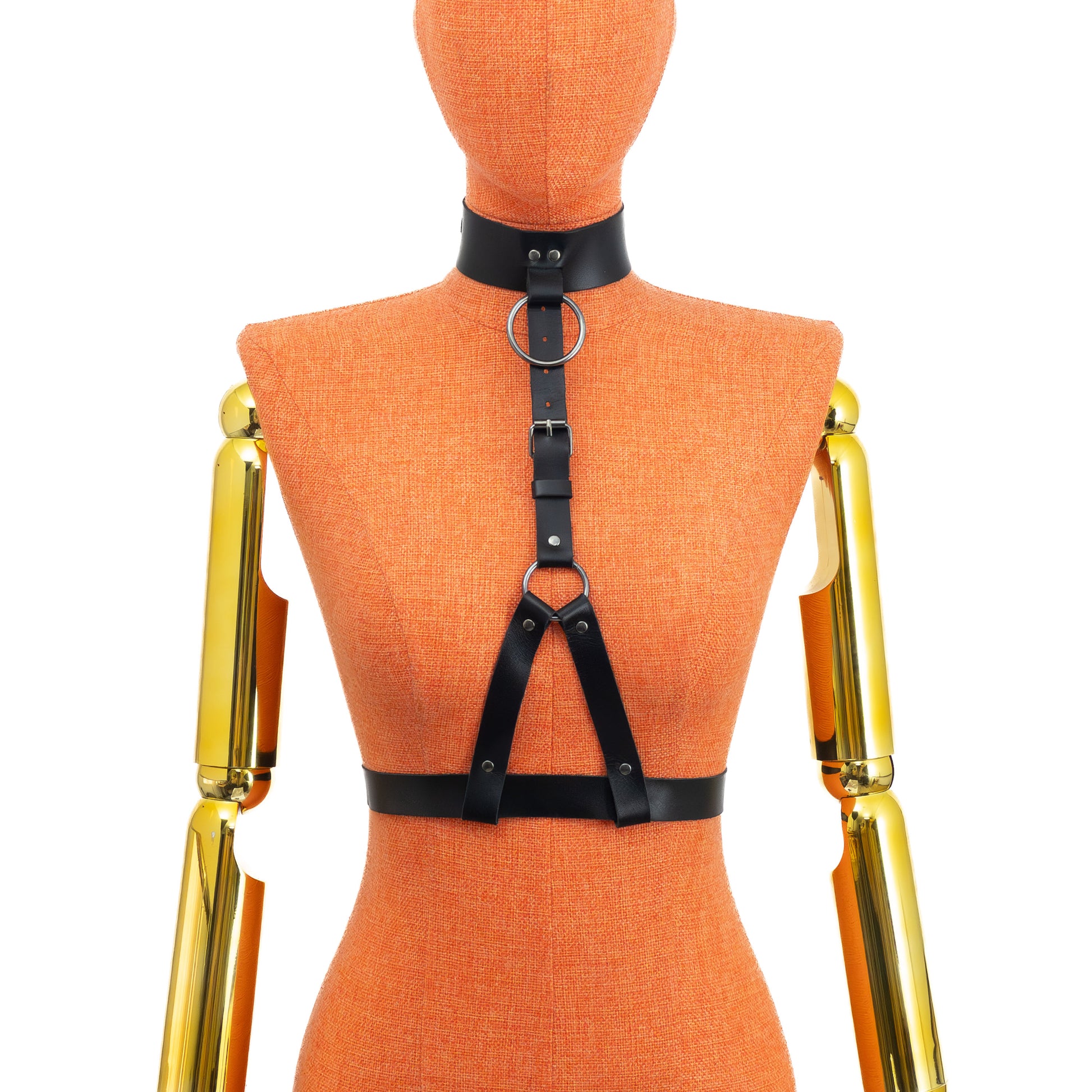 Front view on mannequin of black leather harness with wide collar, central ring at neck, adjustable vertical strap and lower ring with two straps forming loops around 1 inch waist belt; dark nickel hardware visible.