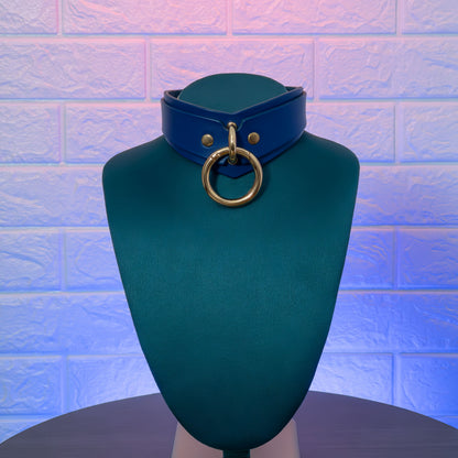 Blue leather choker with gold ring on a green mannequin against a textured blue background