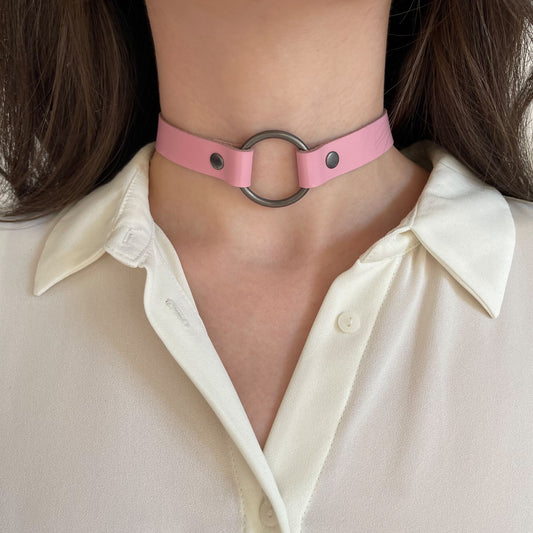 Pink leather choker with dark O-ring – centered front view on white blouse.