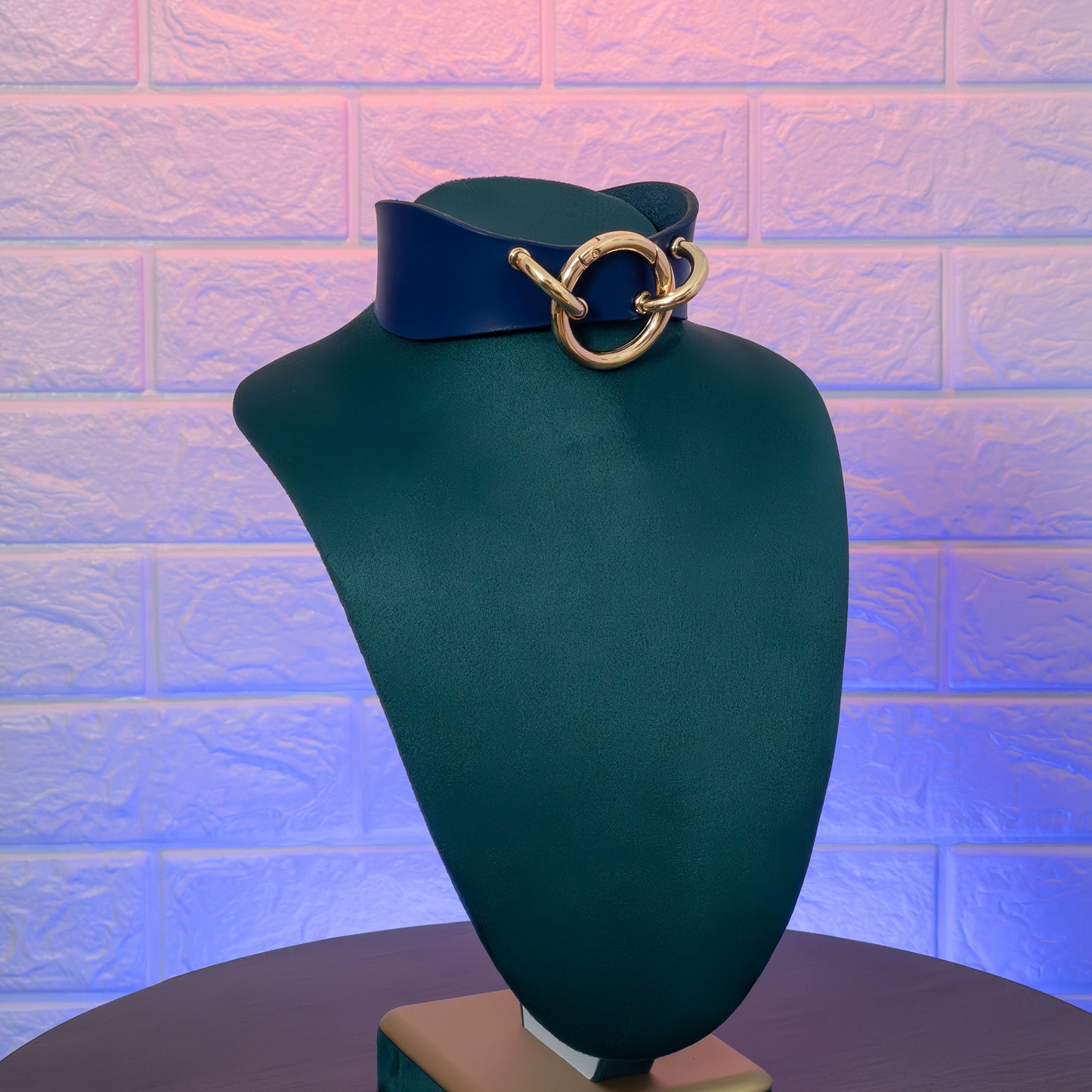 Blue leather  with gold ring on a mannequin bust against a textured purple wall.ollar