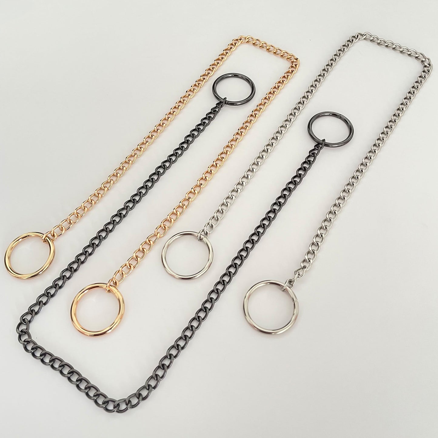 Sliding chain choking collar shown laid out to display all hardware finishes. Three versions are visible: gold-tone metal chain with matching rings, silver-tone chain with silver rings, and dark nickel chain with dark nickel rings. Each collar has two round rings placed at both ends of the chain.