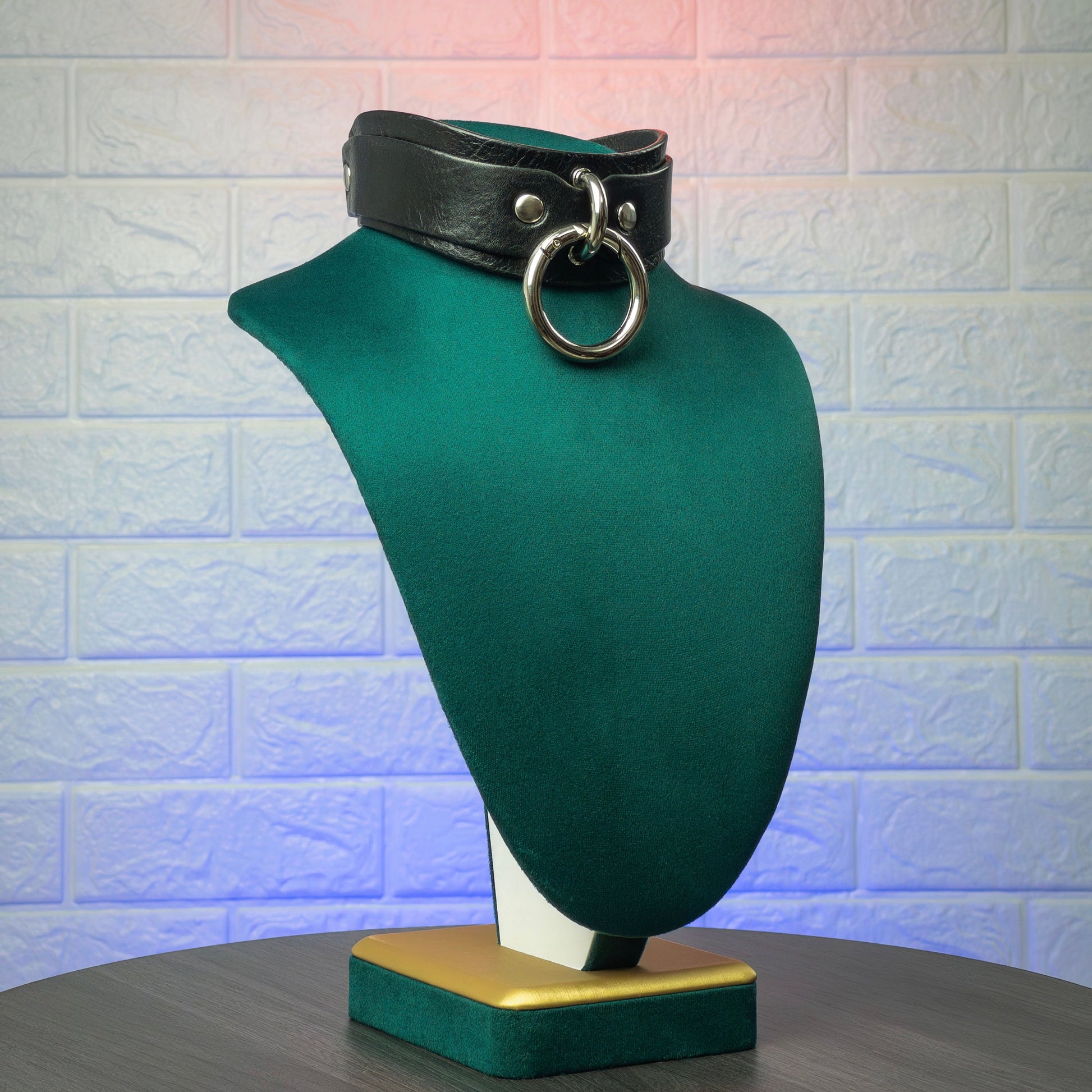 Black leather choker on a green mannequin bust against a textured white wall.