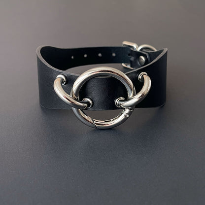 Black leather collar with silver metal rings on a gray background