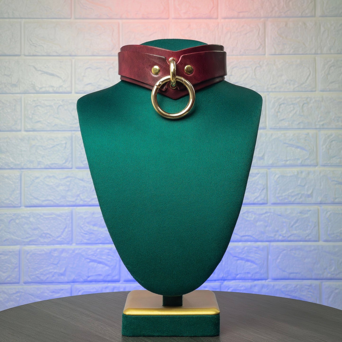Marsala mannequin head with a brown leather belt and gold ring on a textured white background