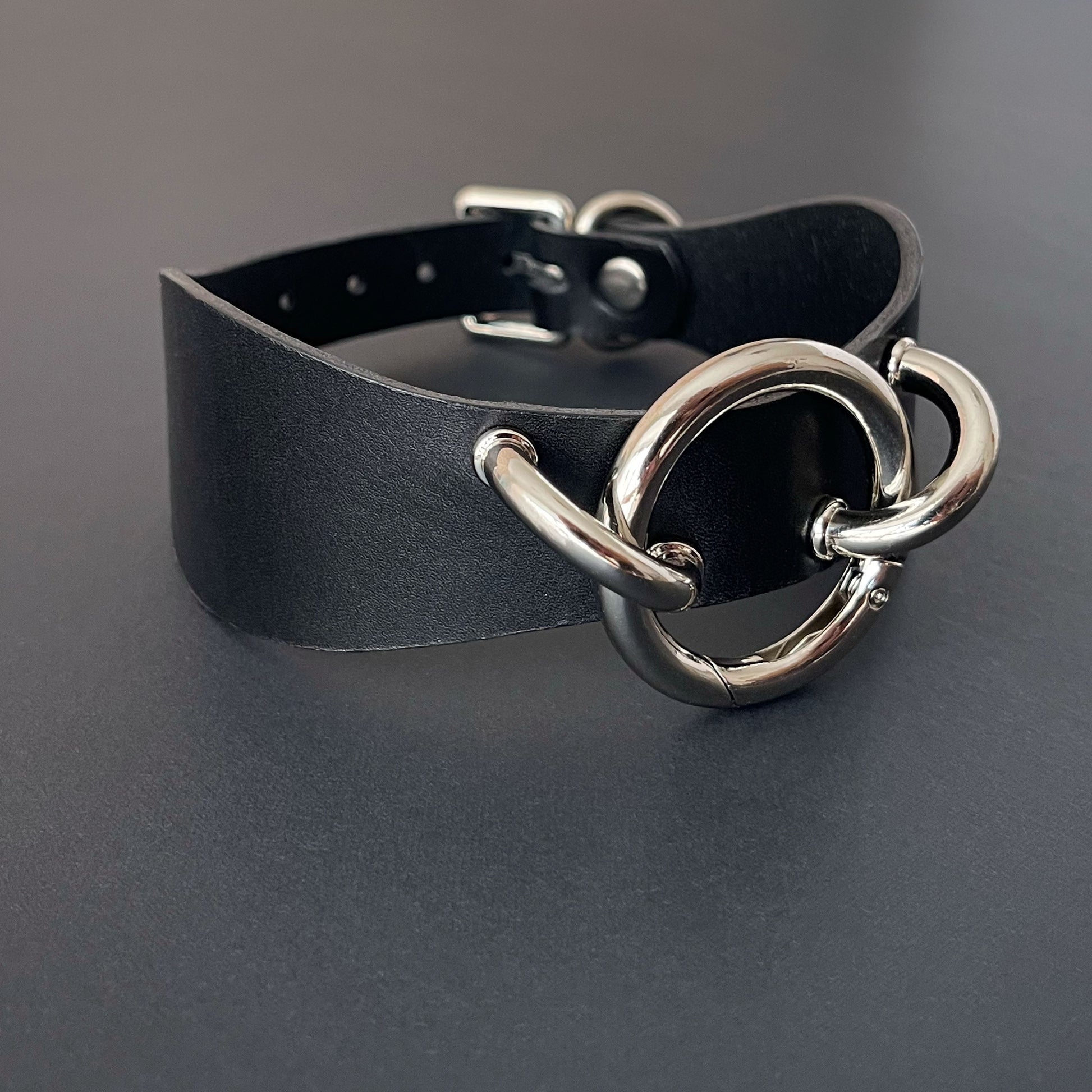 Black leather choker with silver metal clasp on a dark background