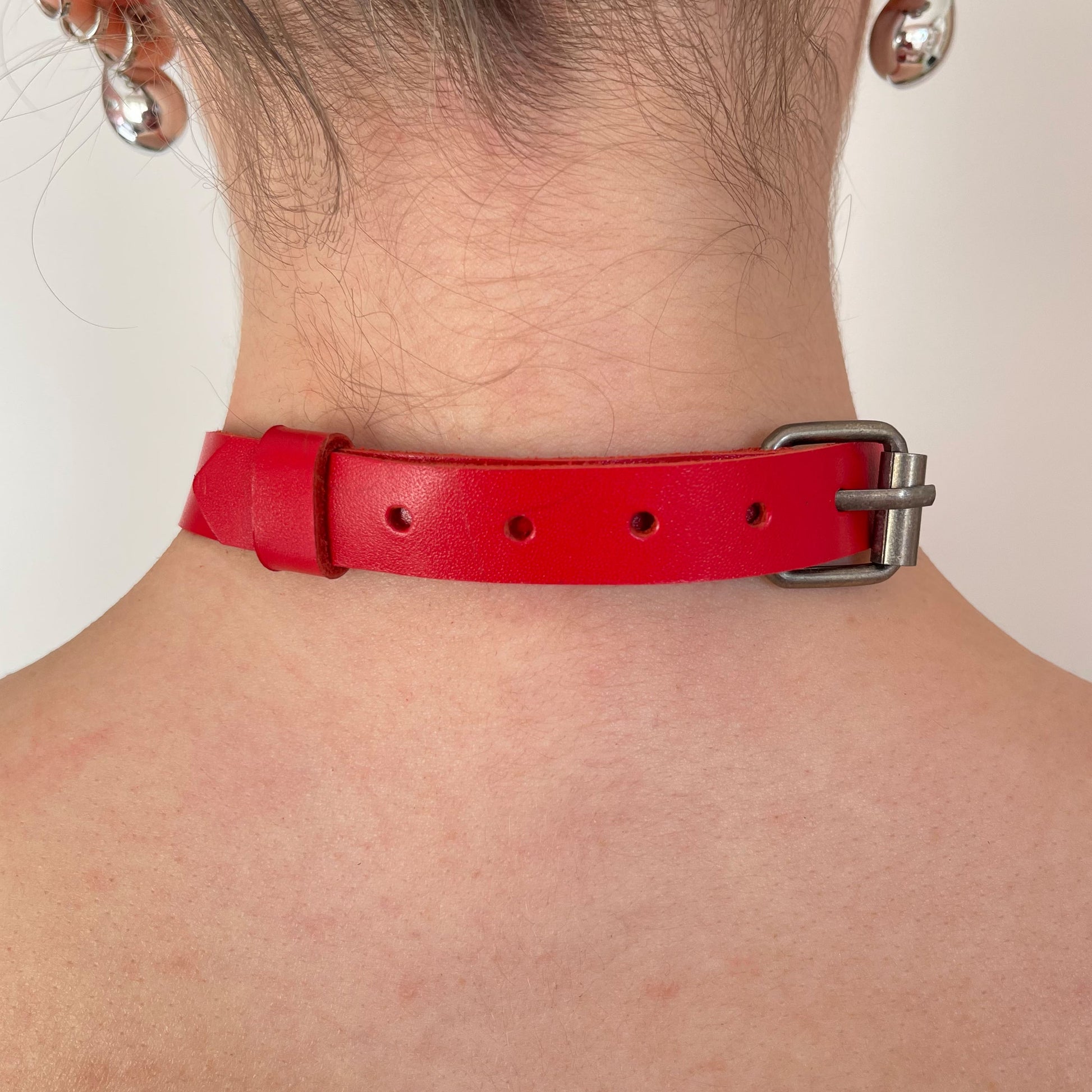 Back view of red leather choker with black buckle and smooth finish.