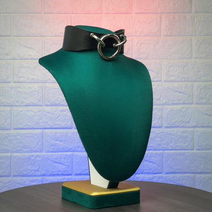 Black leather choker on a mannequin bust against a textured white brick wall.