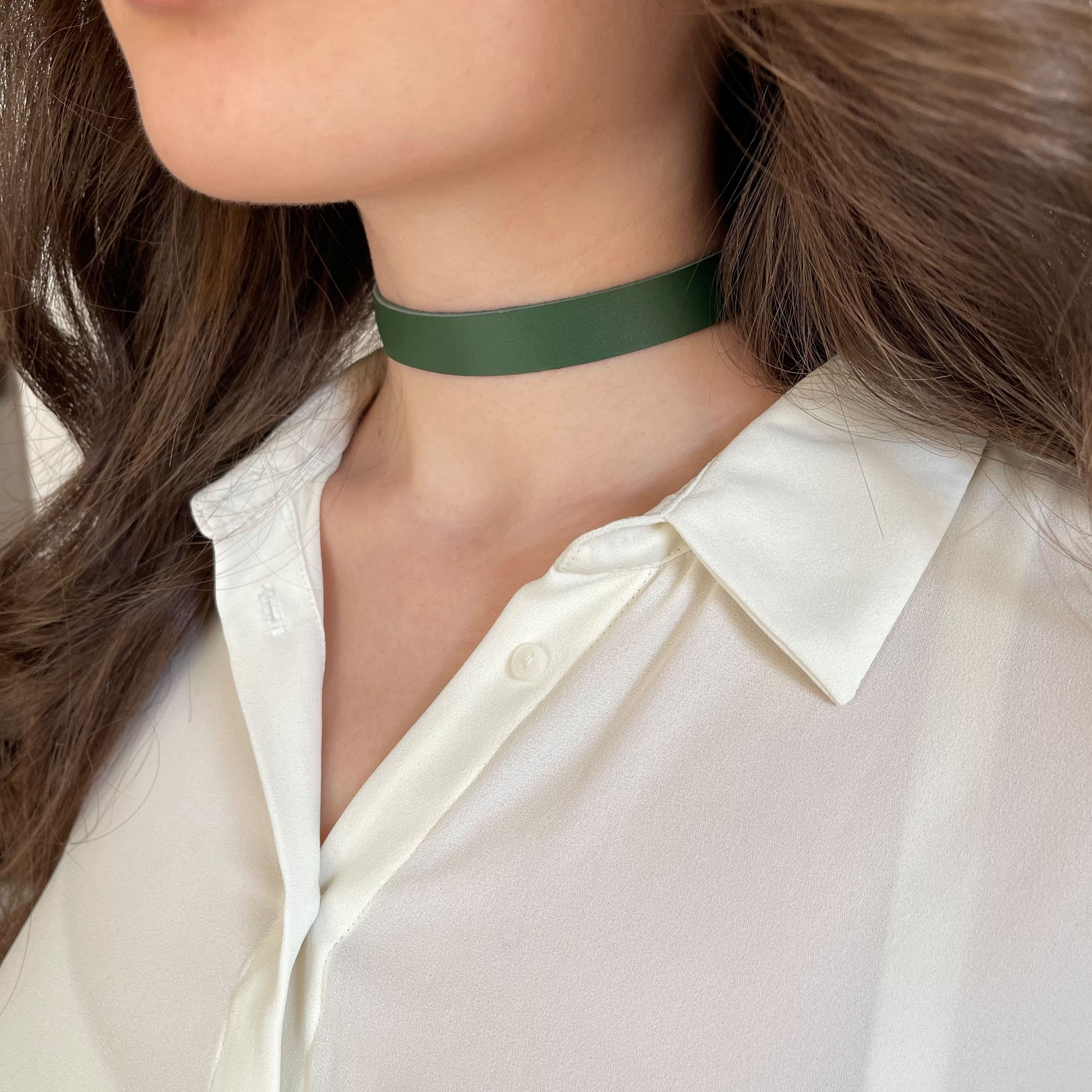Minimalist green leather choker made from genuine semi-matte leather (1.4–1.8 mm thick), 1.5 cm (0.59 in) wide. Secured with a metal buckle. The photo shows a close-up of a woman’s neck in a white shirt, highlighting the deep green tone. A refined everyday accessory in a clean, modern style.