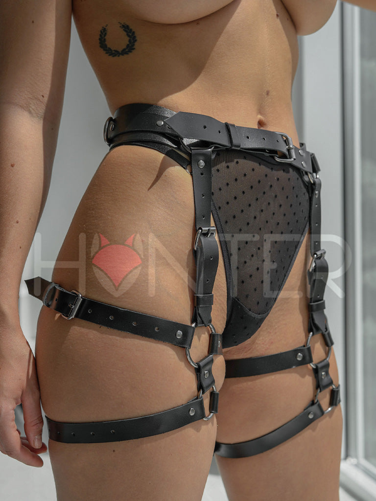 Leather butt garters close-up. Each strap emphasizes the curves of the thighs. The garters are fastened at the waist with a buckle.
Front view, black leather.