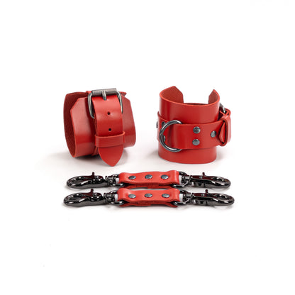 Two red genuine leather ankle cuffs with dark nickel hardware displayed flat, one shown from the buckle fastening side and the other angled to show the metal D-ring. Each cuff has a 6 cm (2.36 in) wide base and a 2.5 cm (0.98 in) strap, with two red leather connectors placed in front.