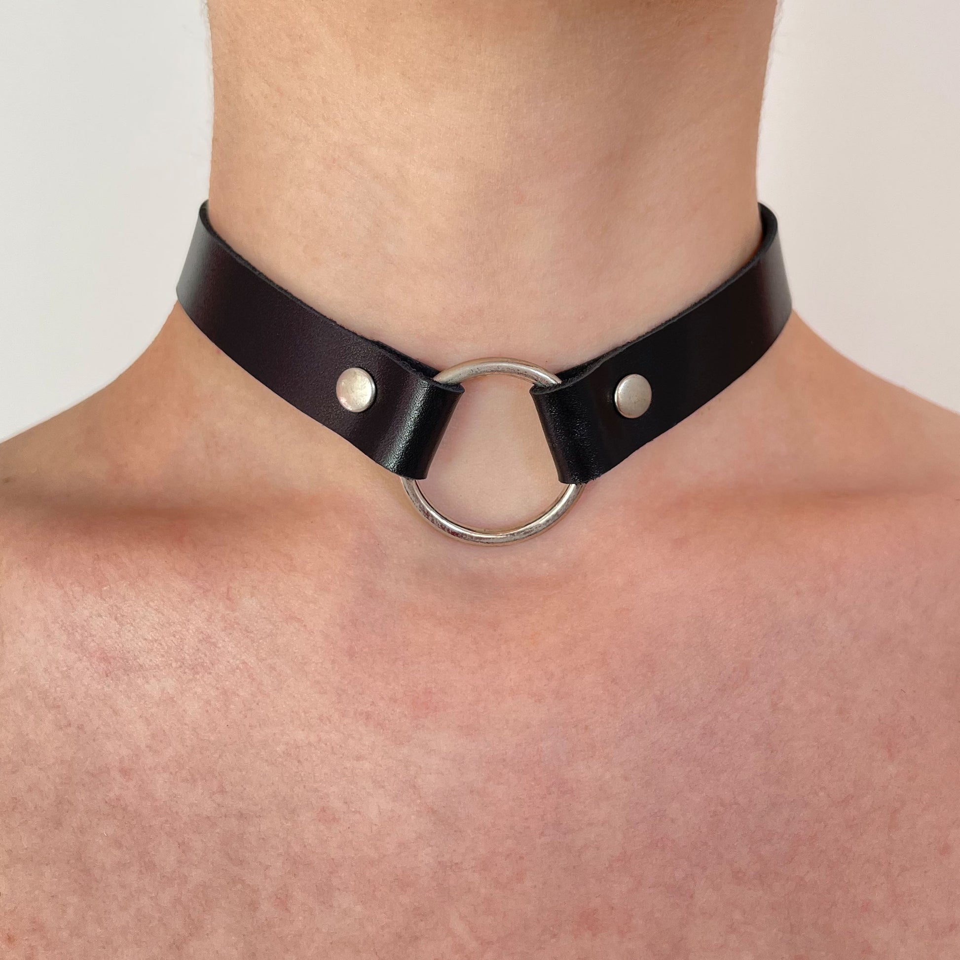Black leather choker with silver ring – centered front view on bare skin