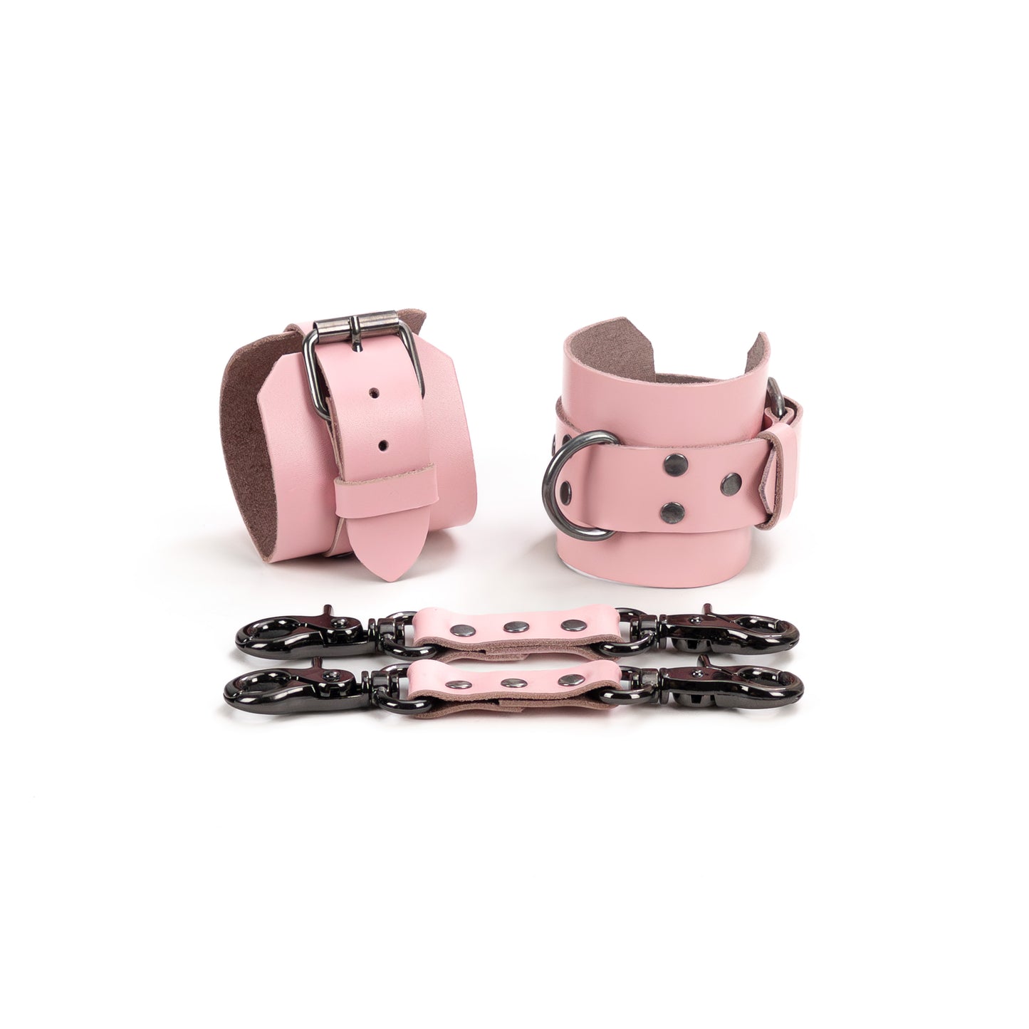 Pink leather handcuffs displayed on a white background with leather connectors and metal carabiners, featuring a 6 cm (2.36 in) wide leather base, 2.5 cm (0.98 in) buckle straps, and D-rings for connection.