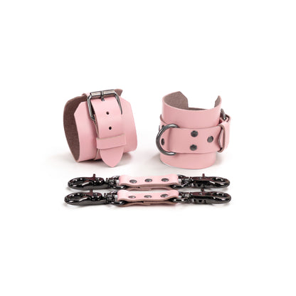 Pink leather handcuffs displayed on a white background with leather connectors and metal carabiners, featuring a 6 cm (2.36 in) wide leather base, 2.5 cm (0.98 in) buckle straps, and D-rings for connection.