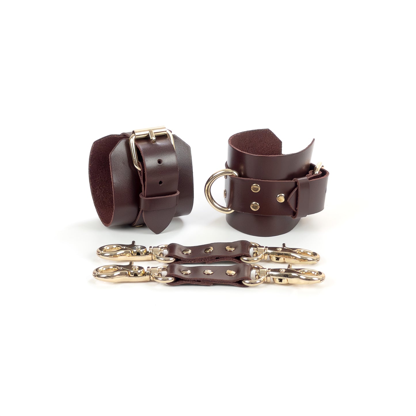 Marsala leather handcuffs with gold-tone hardware shown on a white background, featuring a 6 cm (2.36 in) wide leather base, 2.5 cm (0.98 in) adjustable buckle straps, and 2.5 cm (0.98 in) D-rings, with leather connectors and metal carabiners placed in front.