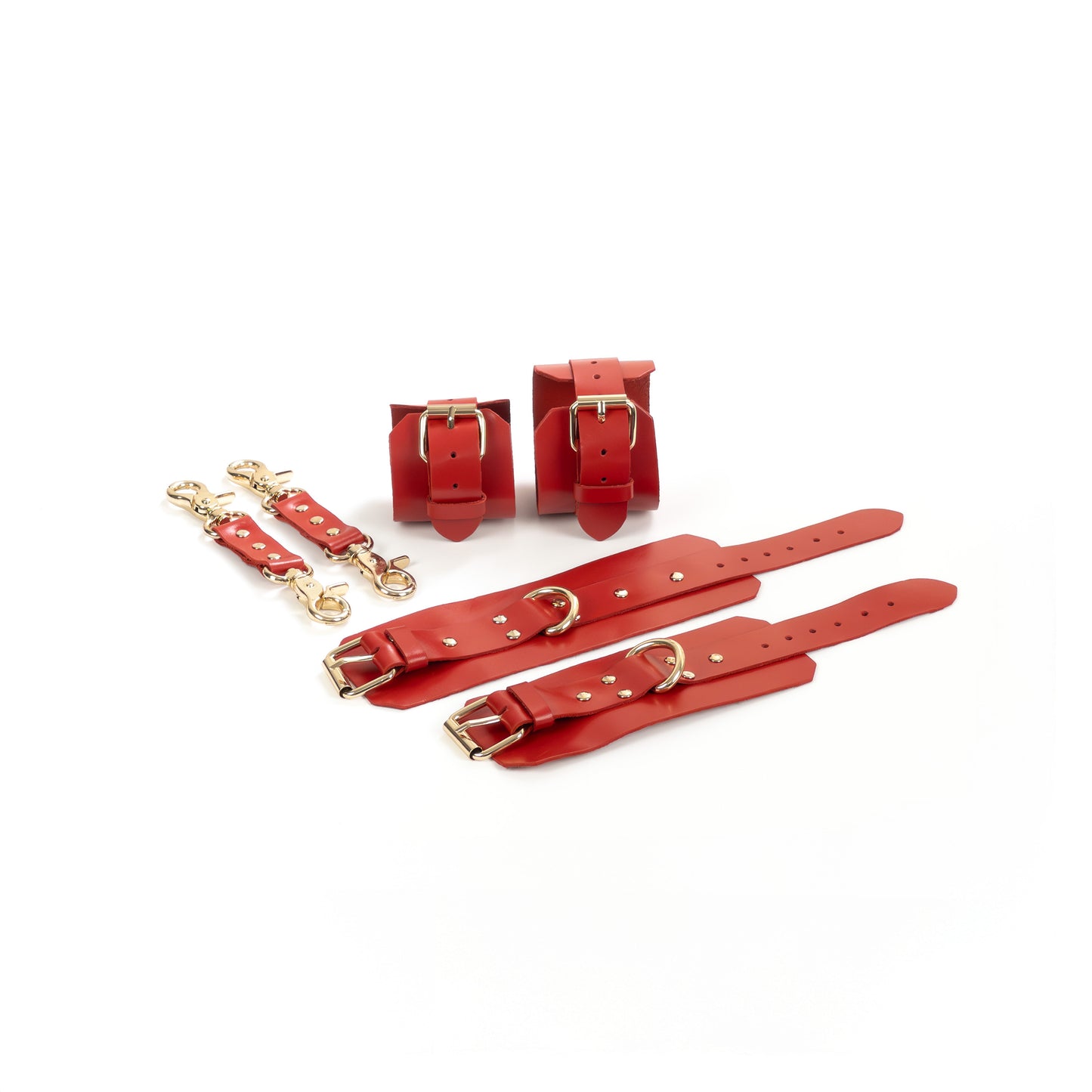 Red leather BDSM set laid flat: wrist cuffs and ankle cuffs with buckle straps, rivets, adjustment holes, and gold-tone hardware. Each cuff has a 2.5 cm D-ring. Two matching leather connectors with gold-tone carabiners on both ends are placed next to the cuffs.