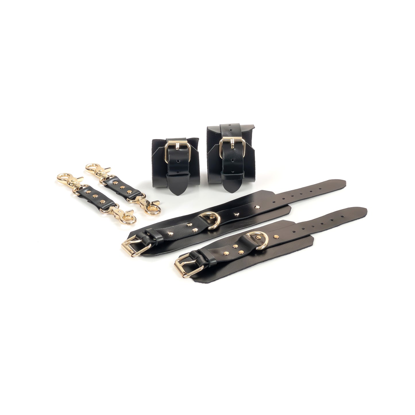 Black leather BDSM set laid flat: wrist cuffs and ankle cuffs with buckle straps, rivets, adjustment holes, and gold-tone hardware. Each cuff shows a 2.5 cm D-ring for attachment. Two matching leather connectors with gold-tone carabiners on both ends are placed to the left.