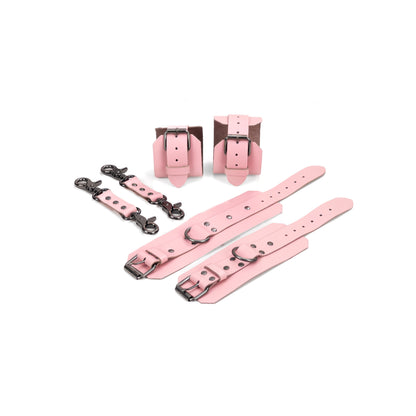 Pink leather BDSM set laid flat: wrist cuffs and ankle cuffs with buckle straps, rivets, adjustment holes, and dark nickel hardware. A 2.5 cm D-ring is visible on each cuff. Two matching leather connectors with dark nickel carabiners on both ends are placed beside the set.