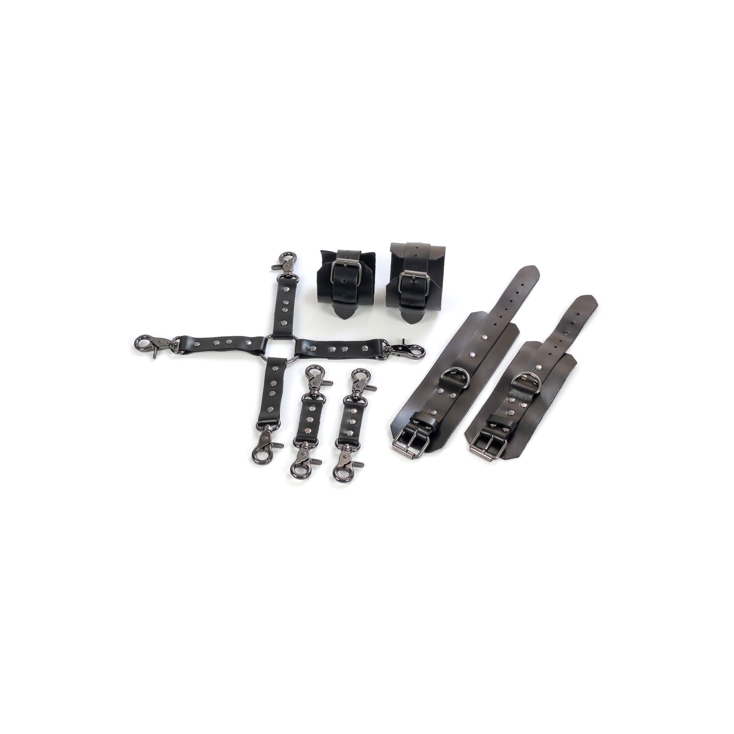 Complete leather restraint set laid out on a white background, black genuine leather with dark nickel hardware, includes handcuffs, ankle cuffs, one four-way connector and two small connectors, cuffs shown opened and fastened to show 2.5 cm straps, buckles and 2.5 cm D-rings.