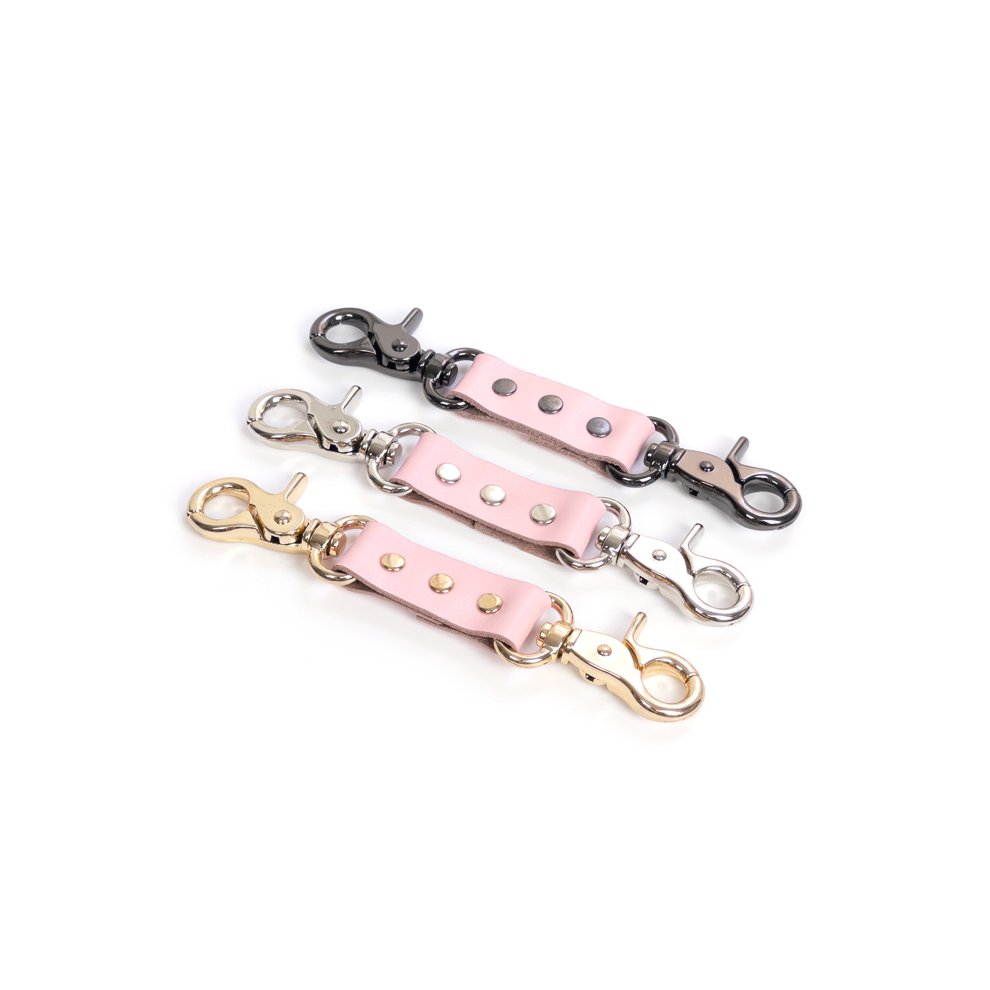 Leather double carabiner connector made of pink genuine leather with metal carabiners fixed on both ends, shown on a white background. The photo presents pink leather combined with gold, silver, and dark nickel carabiners, with the strap laid flat and both carabiners visible from above.