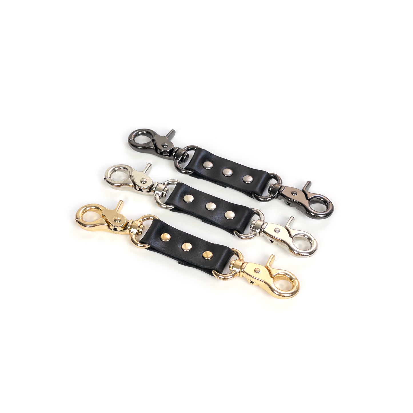 Three small leather connectors shown side by side on a white background, black genuine leather with carabiners, hardware finishes are dark nickel, silver and gold to compare metal colors against the same black leather, top angled view with stitching and rivets visible.