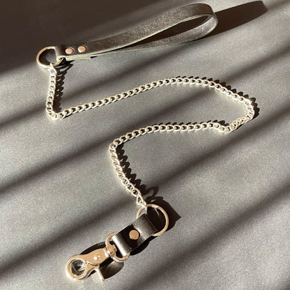 Leather and chain bondage leash on a gray surface