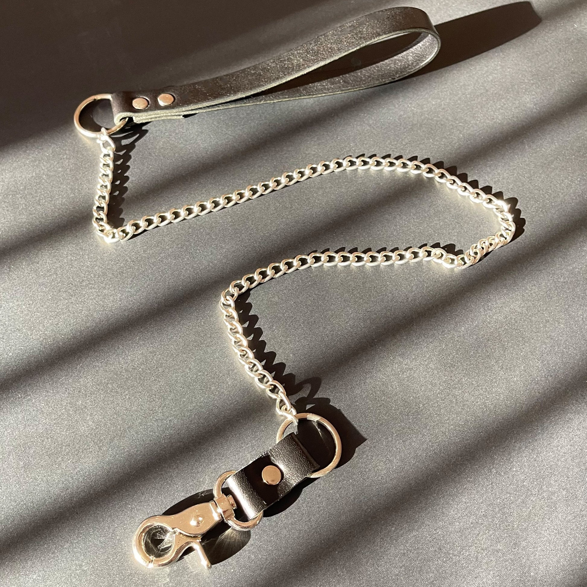 Leather and chain bondage leash on a gray surface