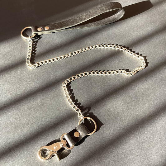 Leather and chain bondage leash on a gray surface