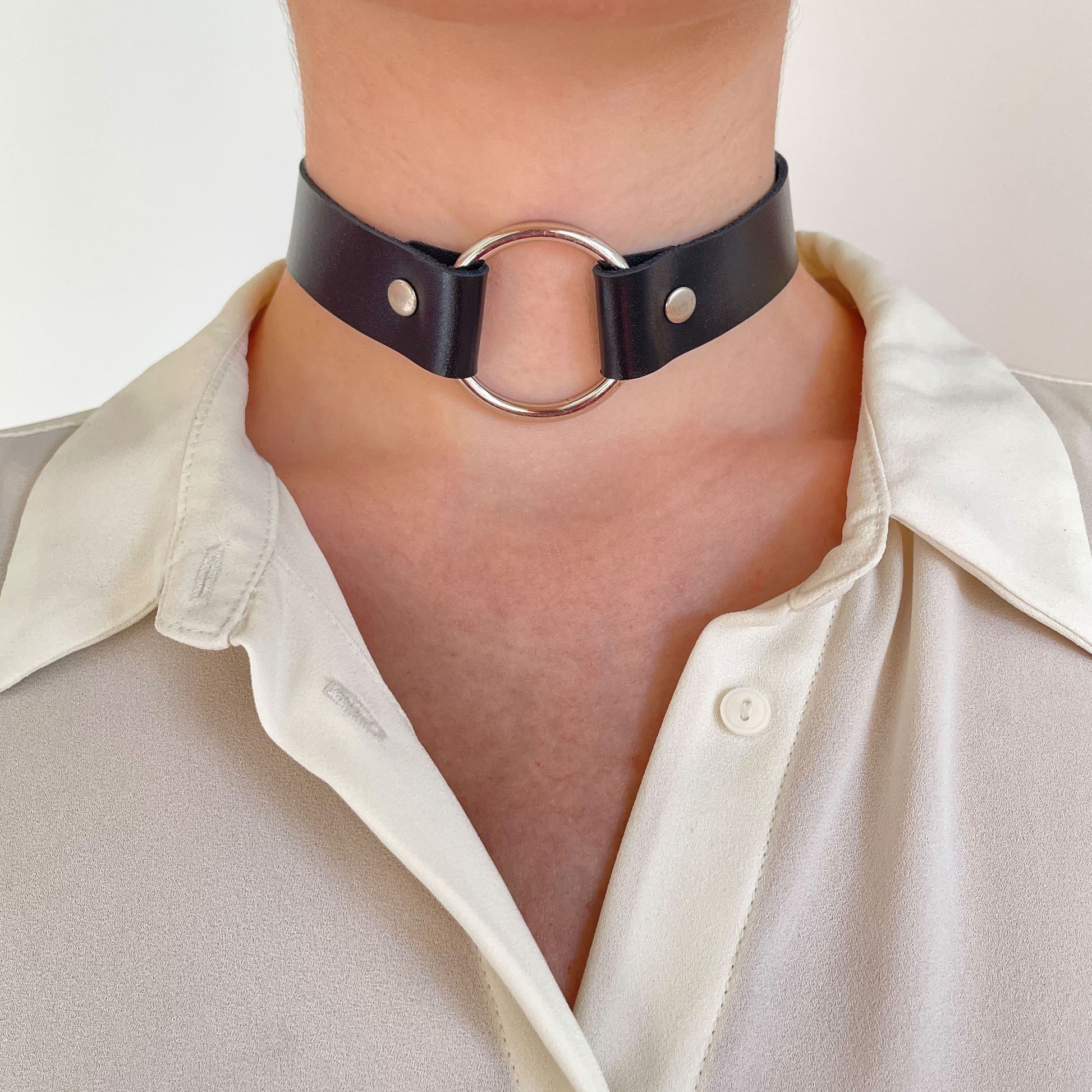Full front view of black choker with silver O-ring and rivets, centered on neck
